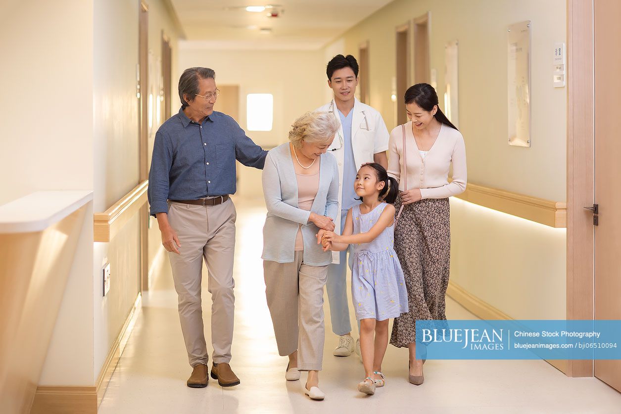 Chinese family and doctor walking in hospital corridor