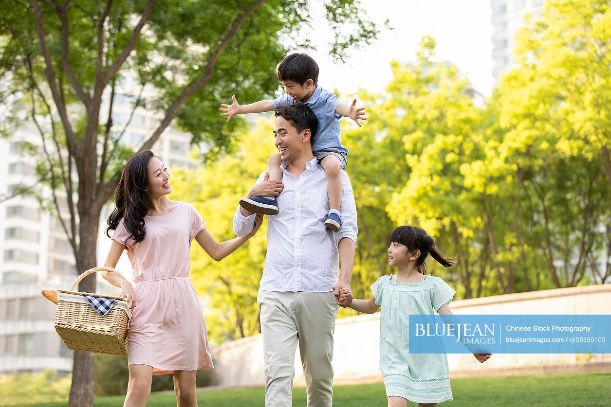 Happy young Chinese family having picnic in park