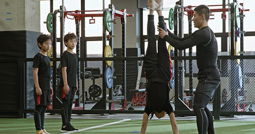 Active Chinese children having exercise class with their coach in gym,4K