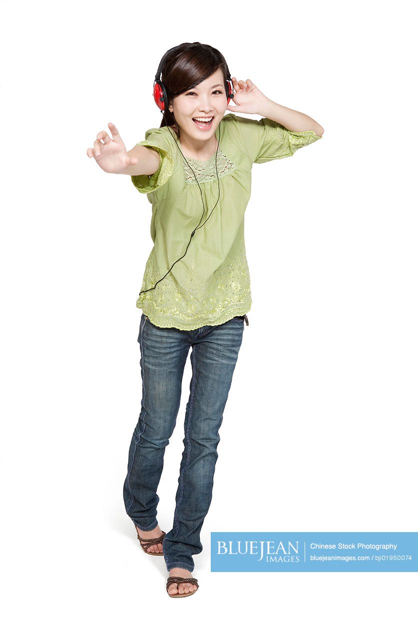 Portrait of young Chinese woman with headphones reaching towards camera