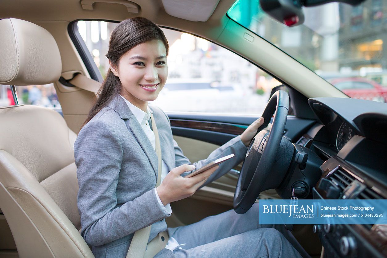 Chinese businesswoman holding smart phone in a car