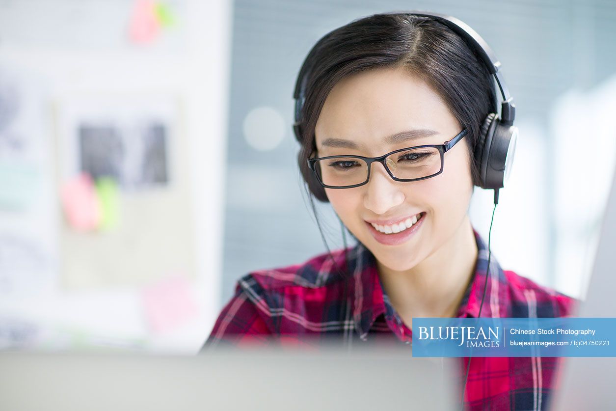 Young Chinese woman listening to music in office