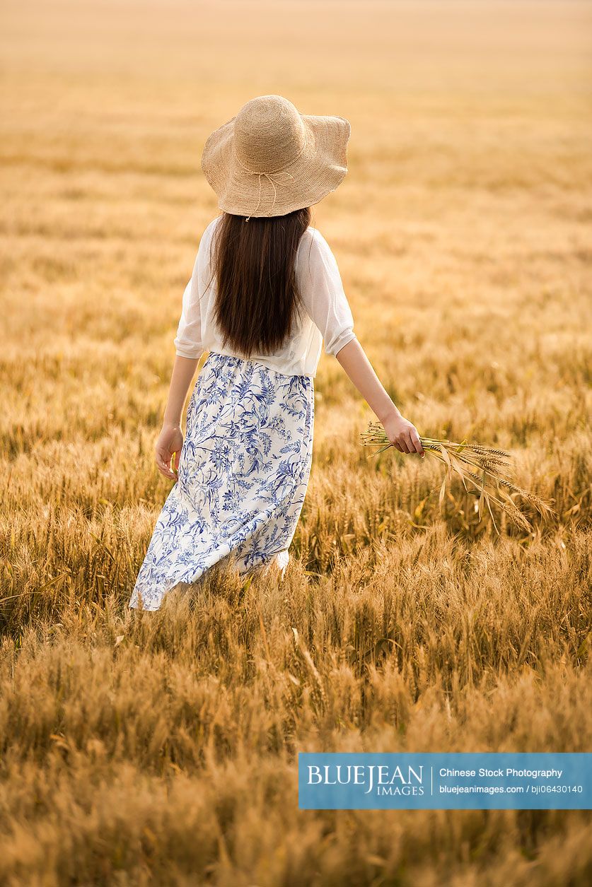 Happy young Chinese woman in wheat field