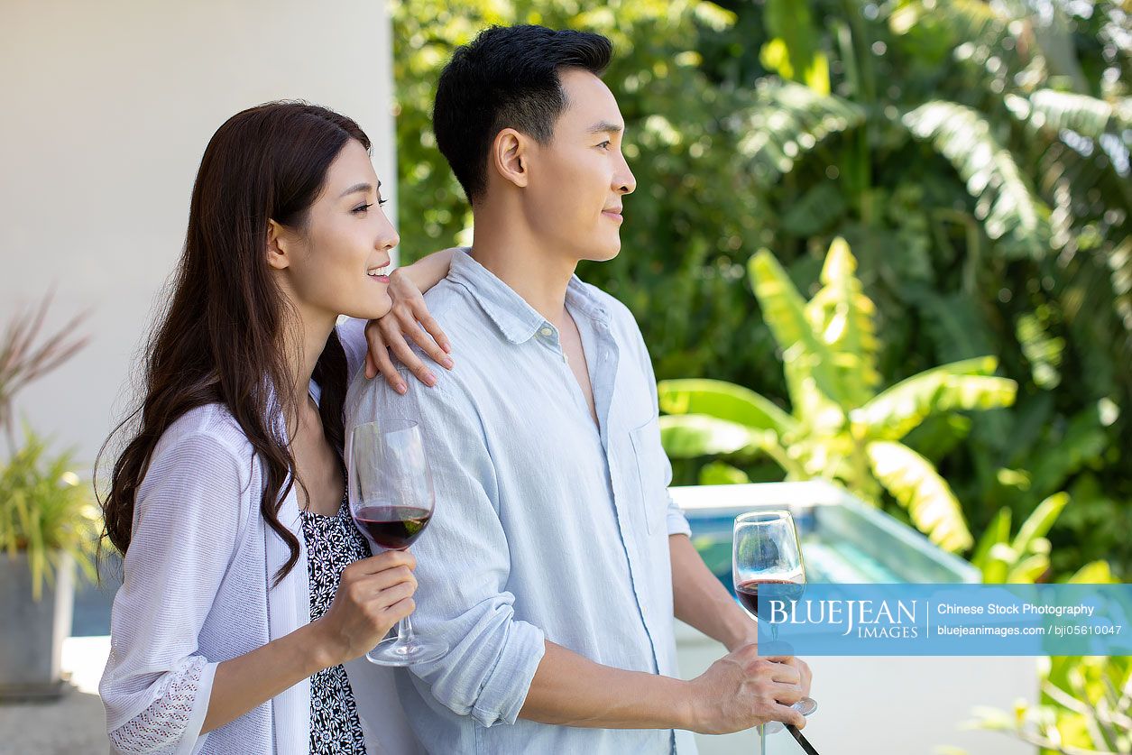Happy young Chinese couple drinking wine on balcony