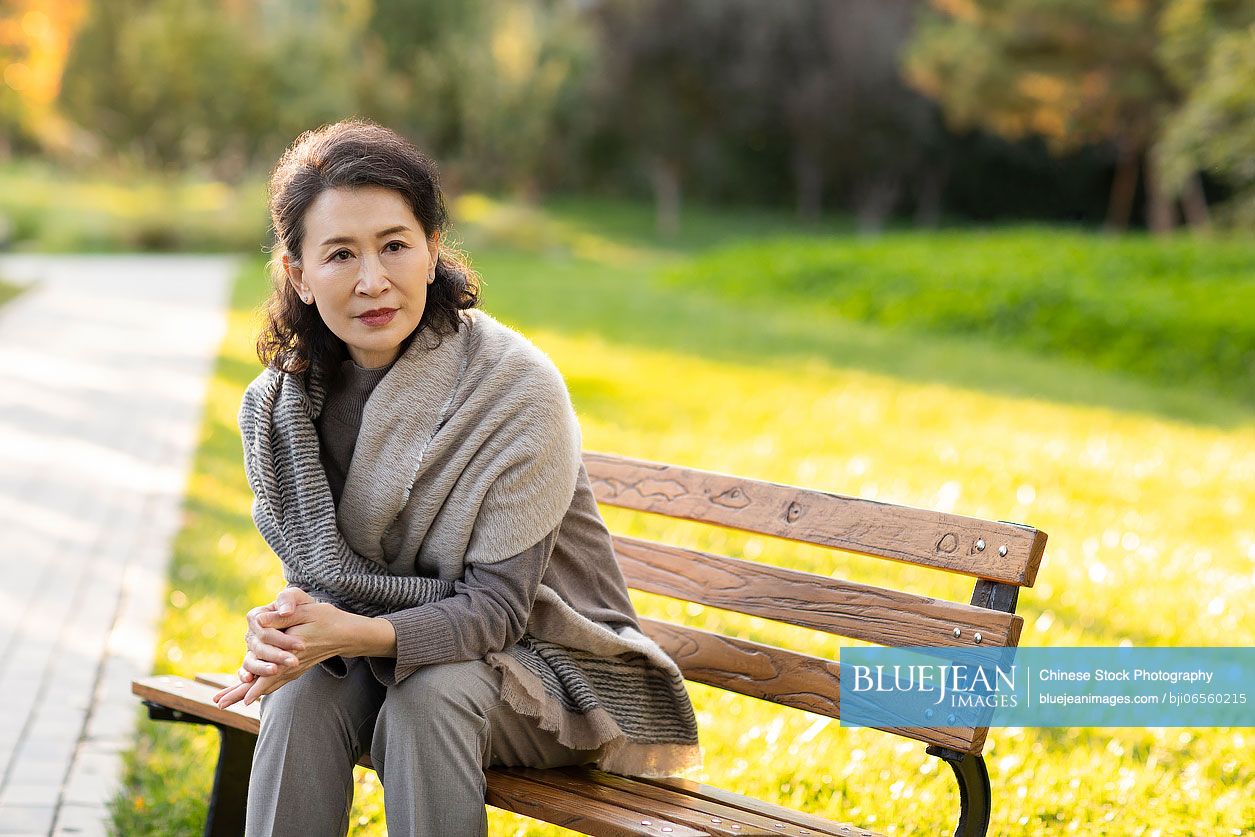 Senior Chinese woman sitting on park bench