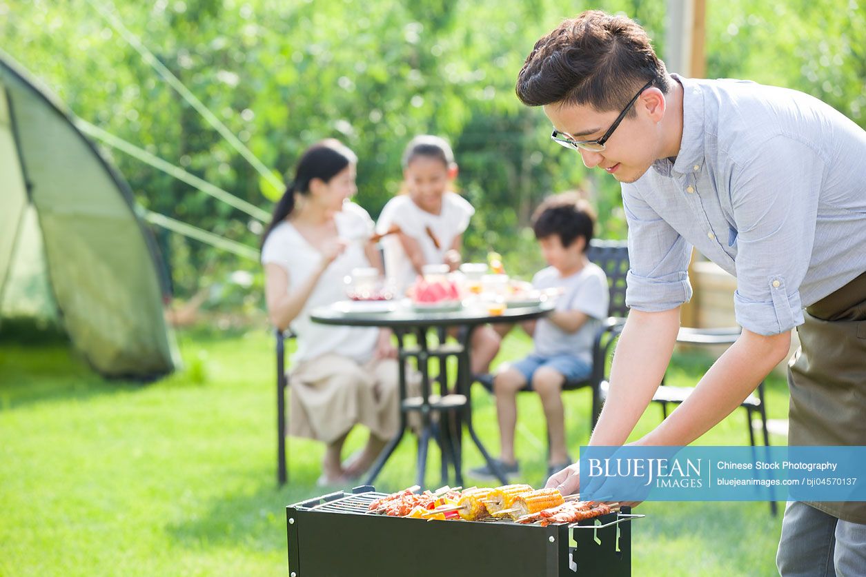 Young Chinese family barbecuing outdoors