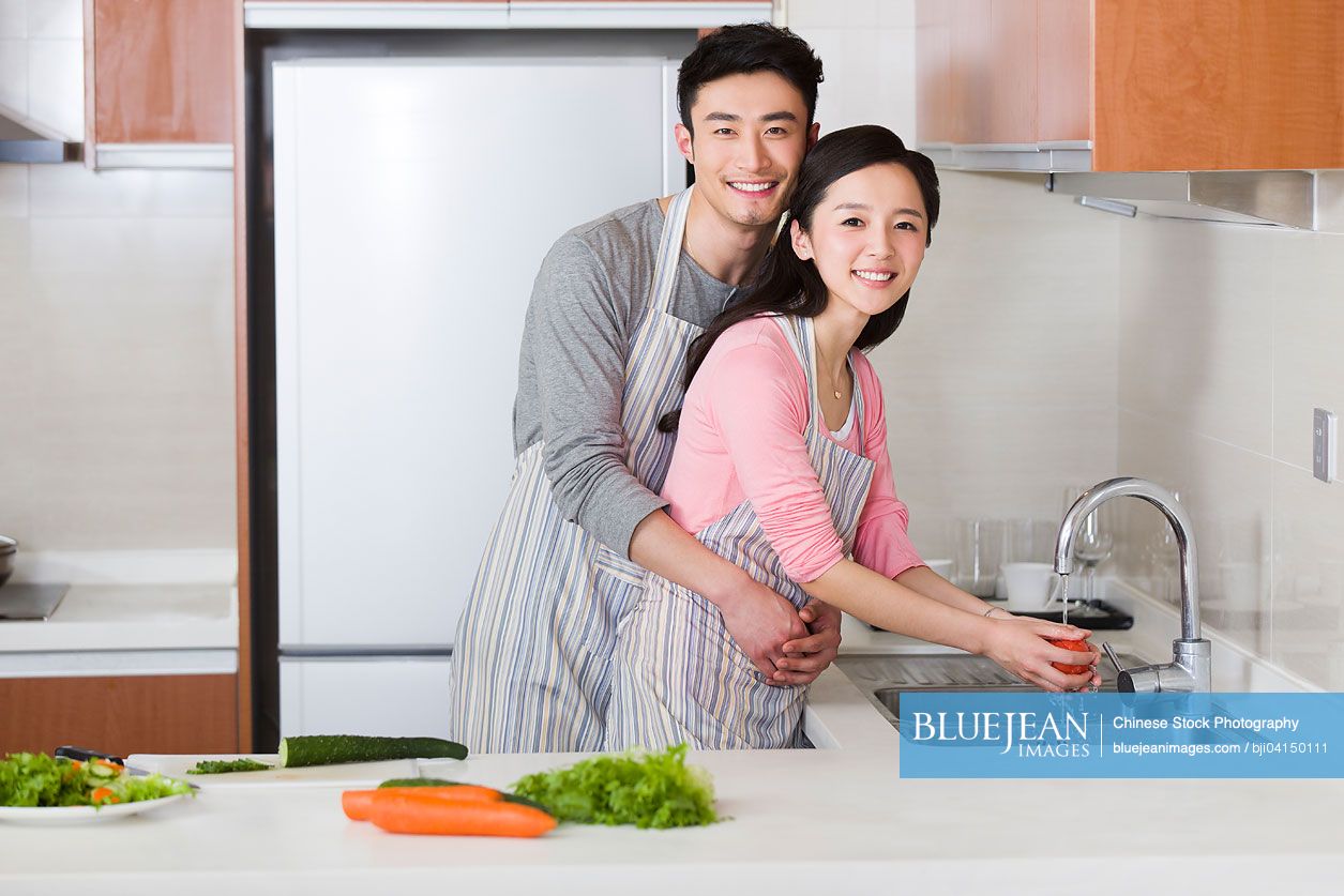 Happy young Chinese couple preparing meal