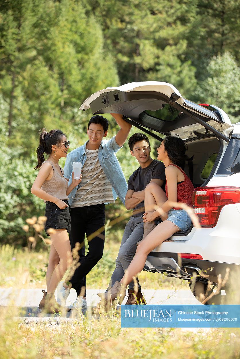 Happy young Chinese friends enjoying road trip