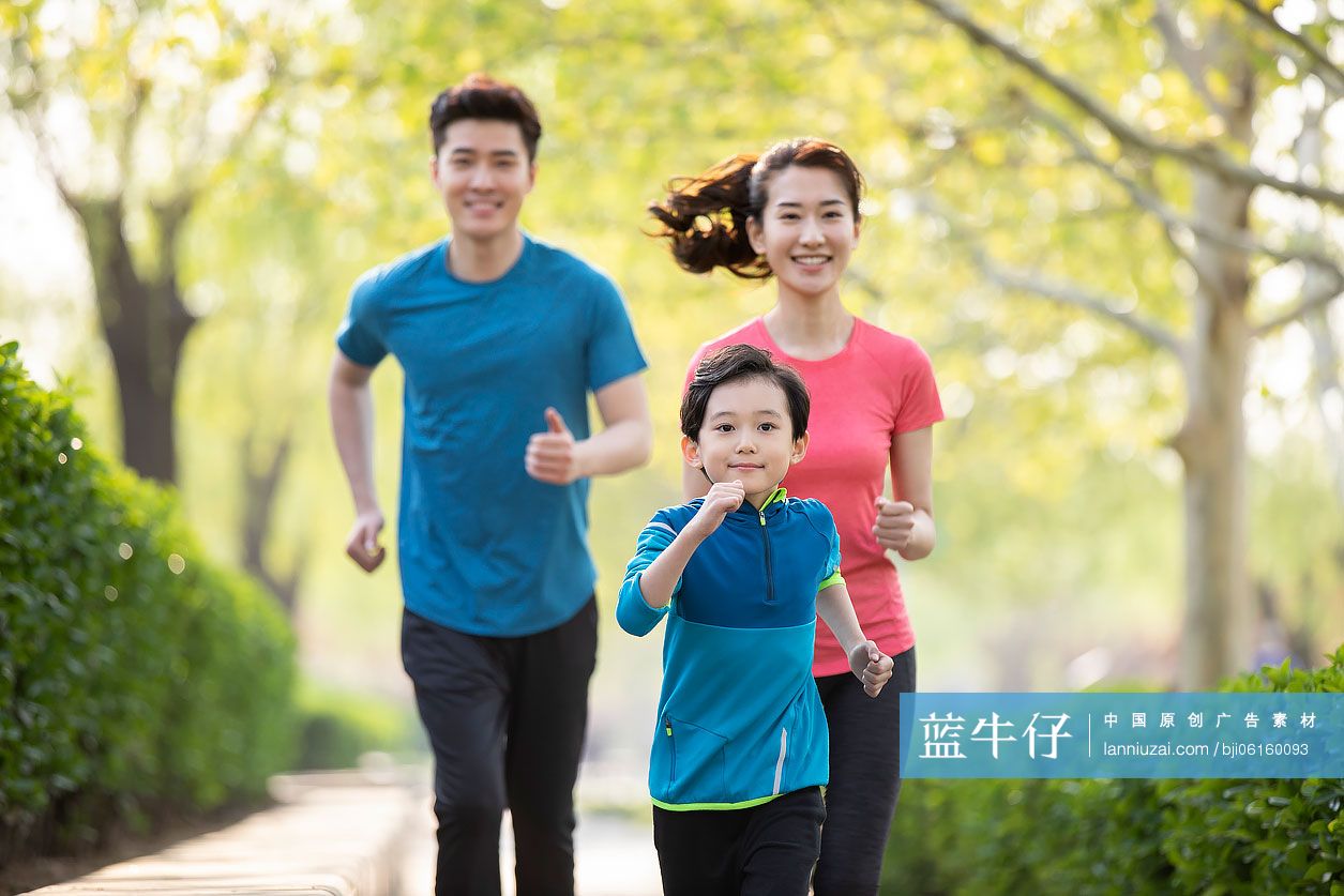 快乐的年轻家庭在公园跑步