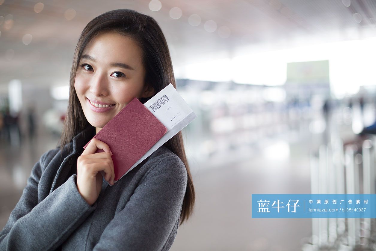 年轻商务女子在机场拿着机票和护照