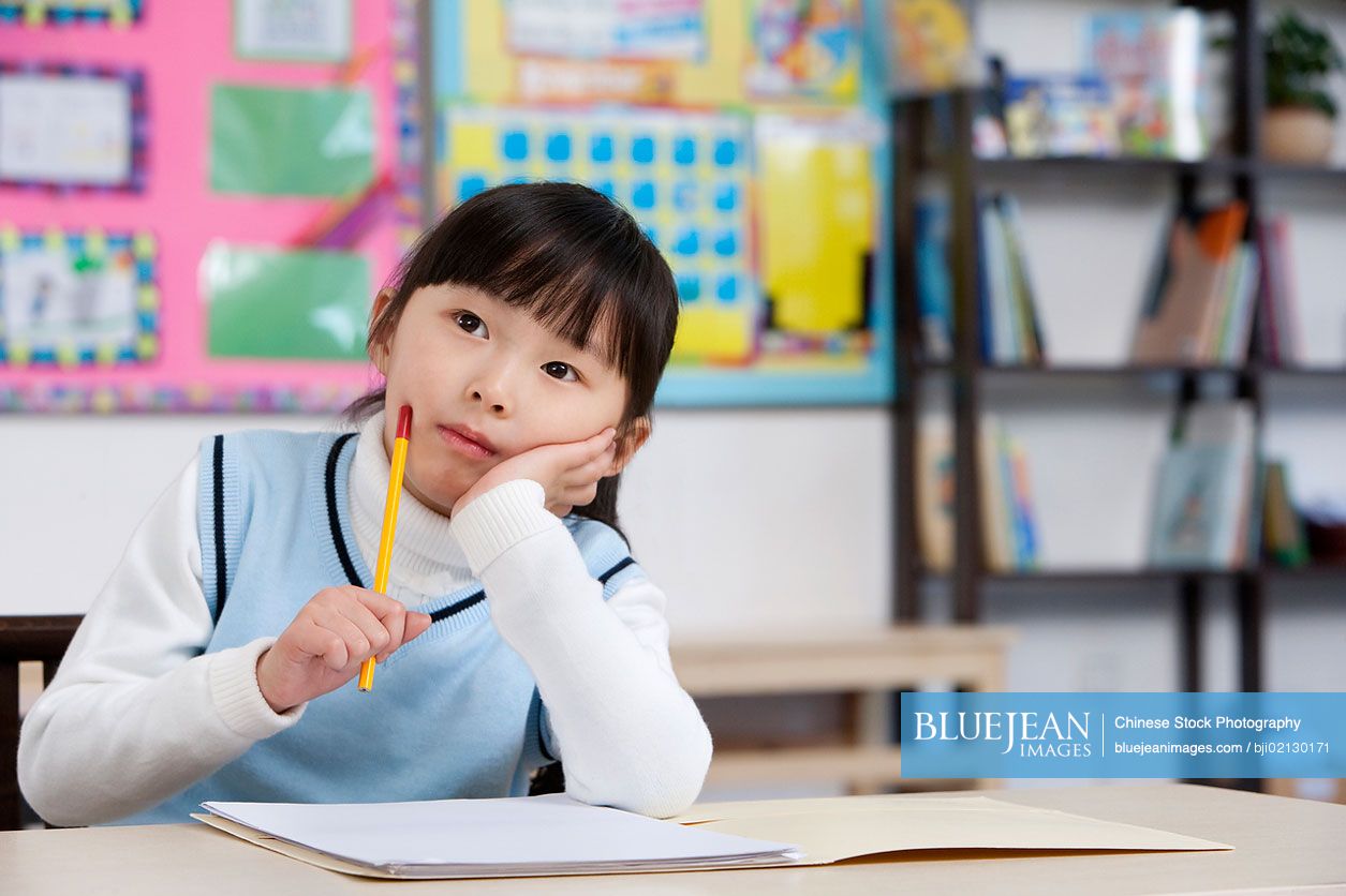 Young Chinese student thinking in classroom