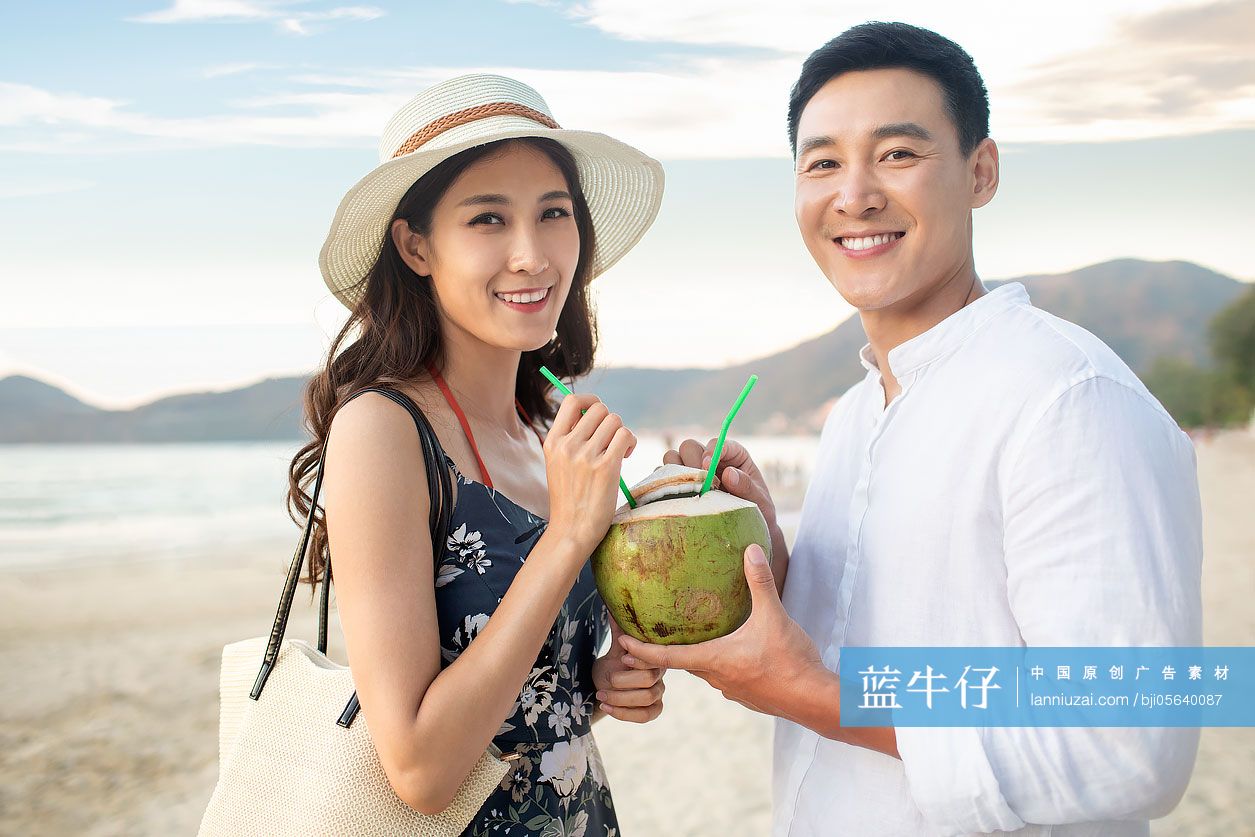 快乐的年轻情侣在沙滩喝椰汁
