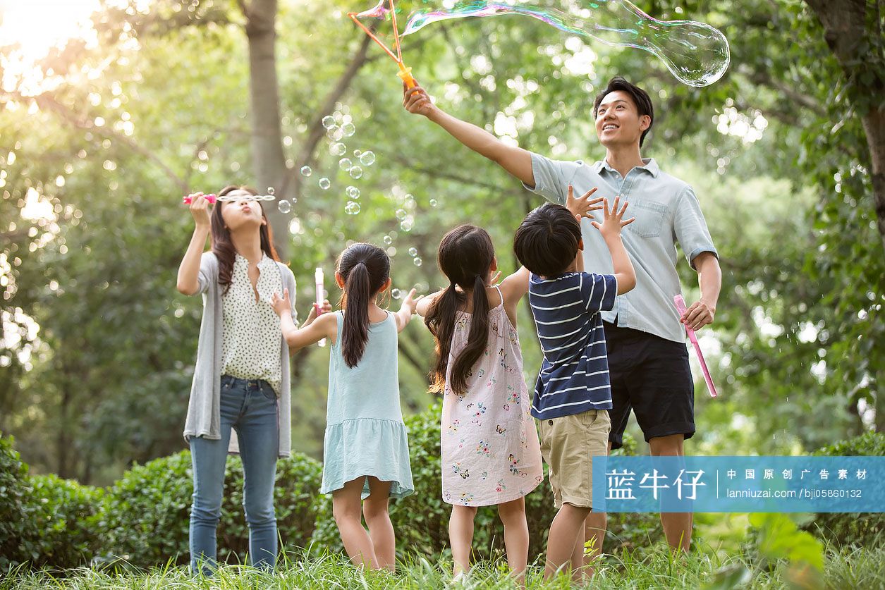 快乐年轻家庭在草地上吹泡泡