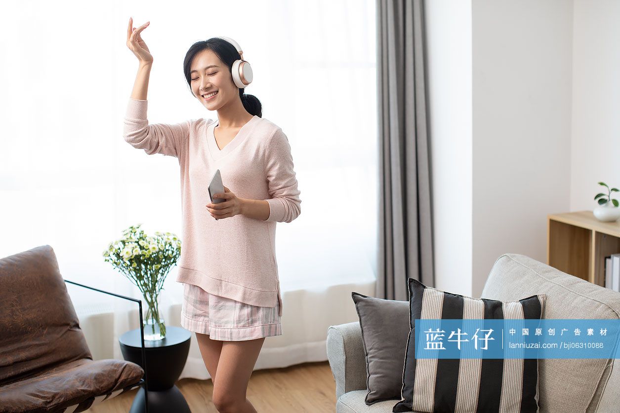 快乐年轻女士在家戴着耳机听音乐