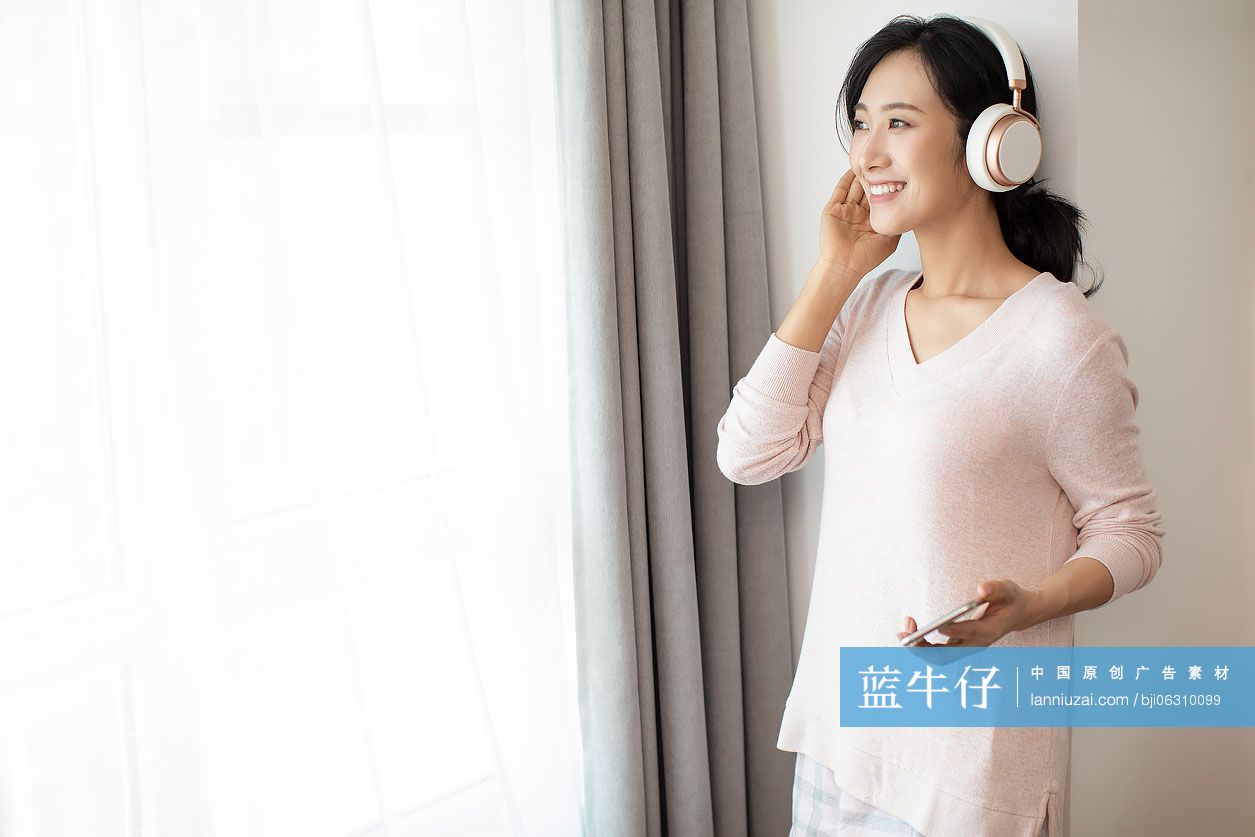 快乐年轻女士在家戴着耳机听音乐