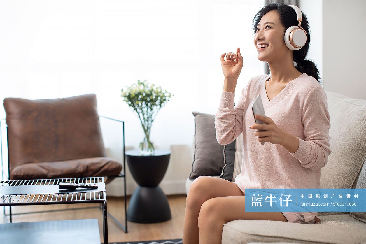 快乐年轻女士在家戴着耳机听音乐