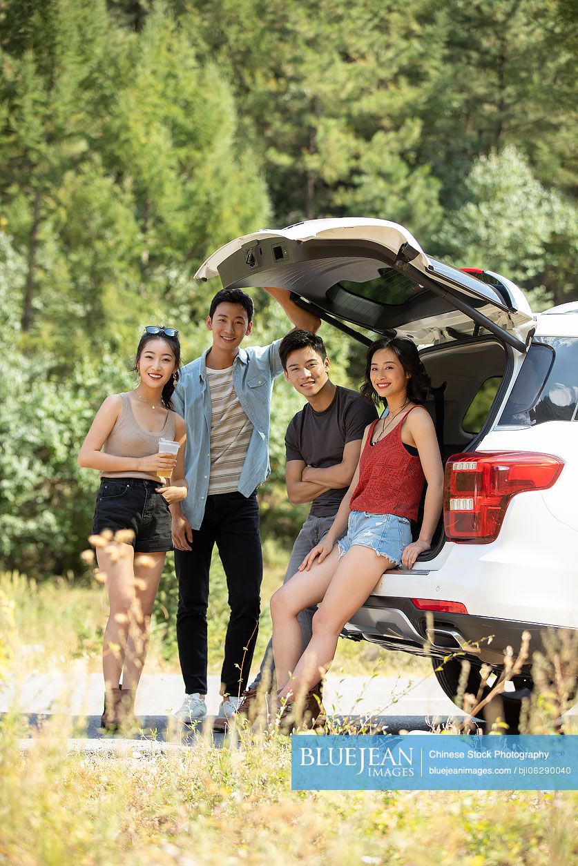 Happy young Chinese friends enjoying road trip