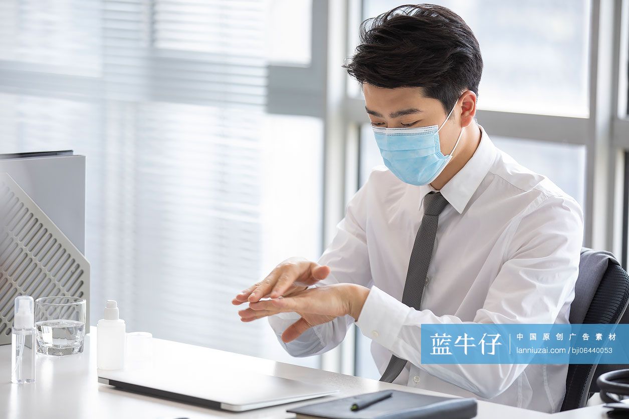 年轻的商务男士在办公室使用免洗洗手液