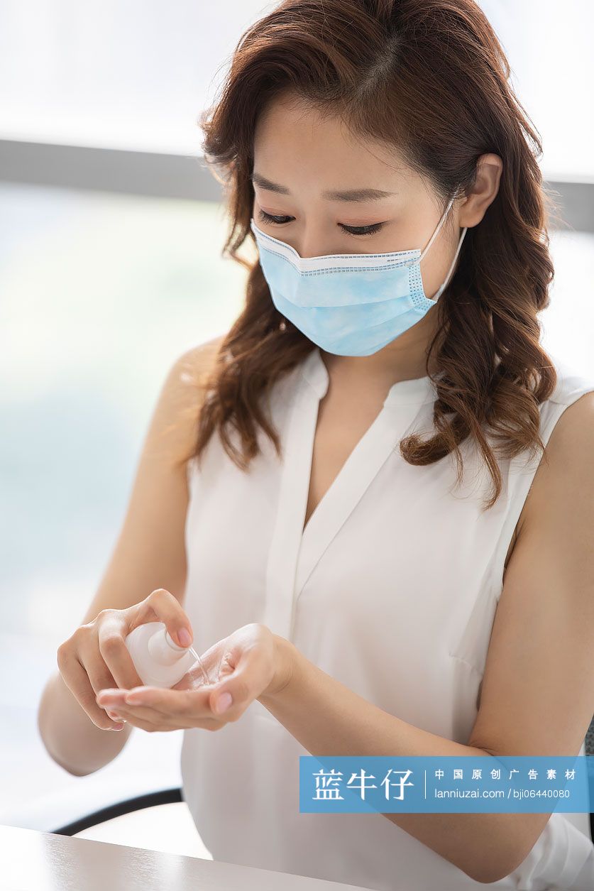 年轻的商务女士在办公室使用免洗洗手液