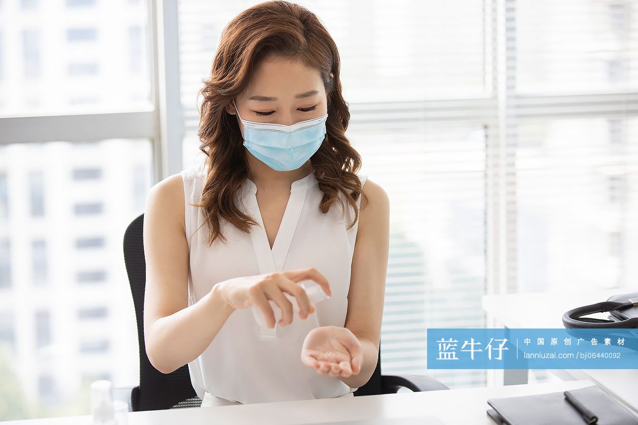 年轻的商务女士在办公室使用免洗洗手液