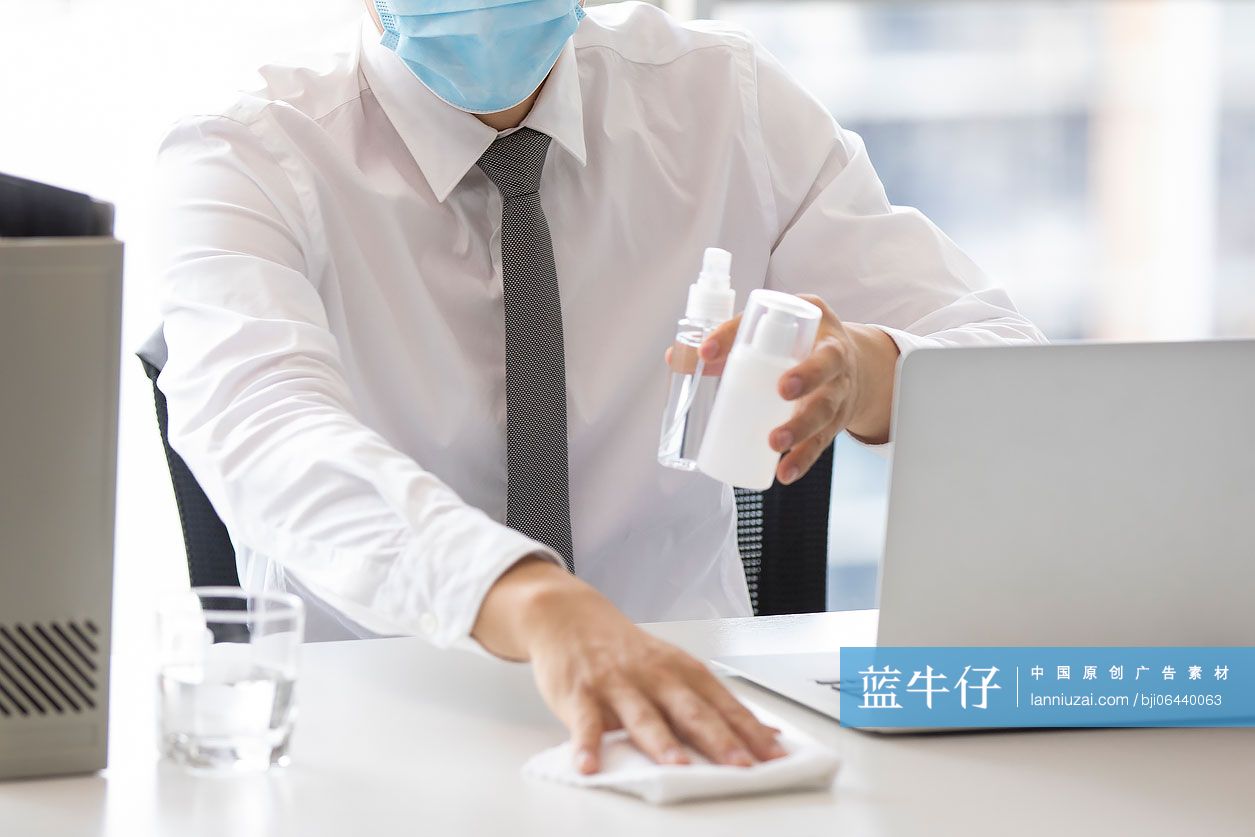 年轻的商务男士在办公室使用消毒液杀菌消毒