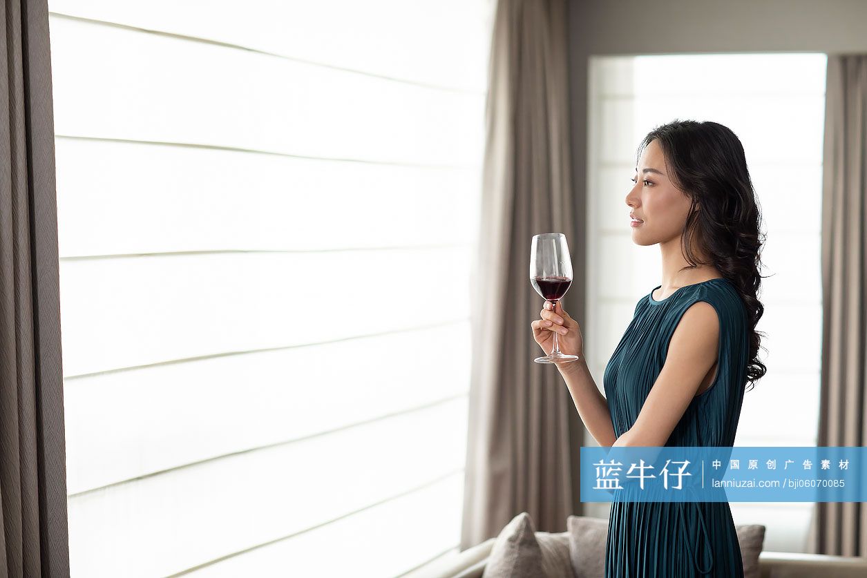 快乐的年轻女士在客厅喝红酒