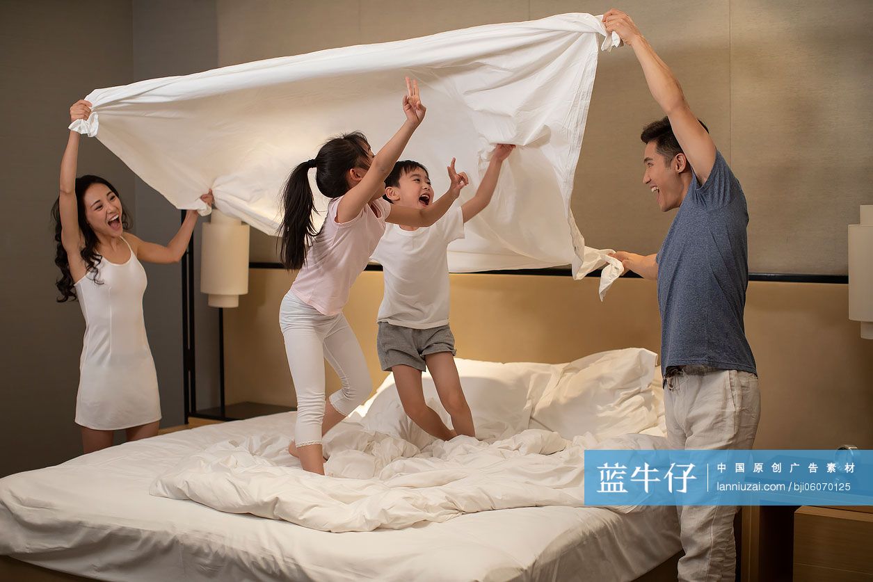 快乐的年轻家庭在卧室玩耍