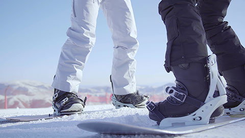 年轻男子教女朋友单板滑雪