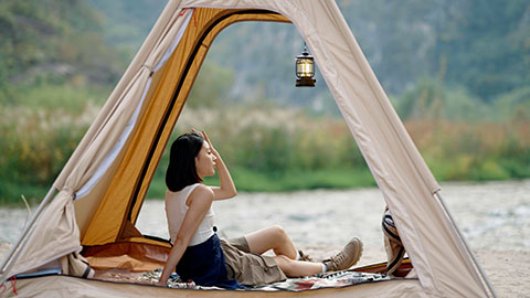 Cheerful young Chinese woman looking out from tent