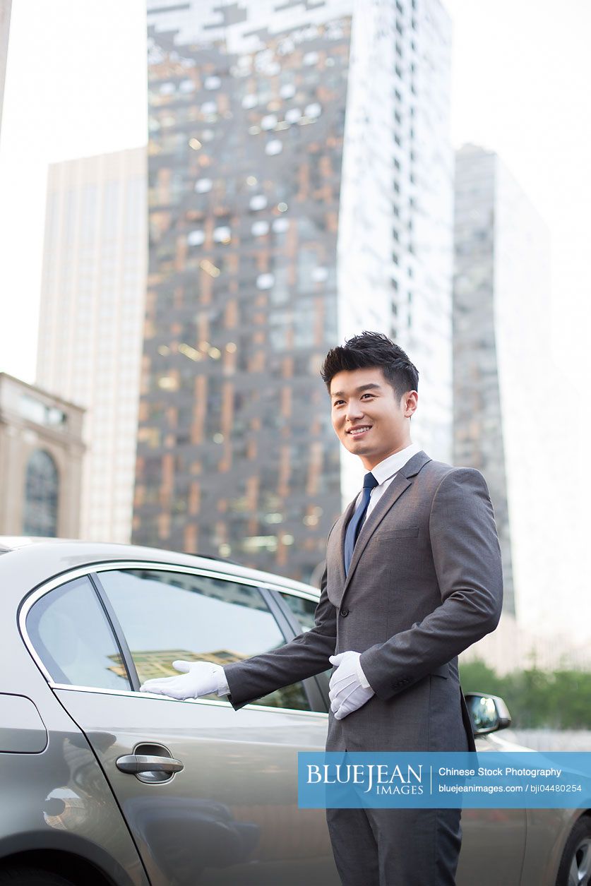 Chinese chauffeur greeting next to the car