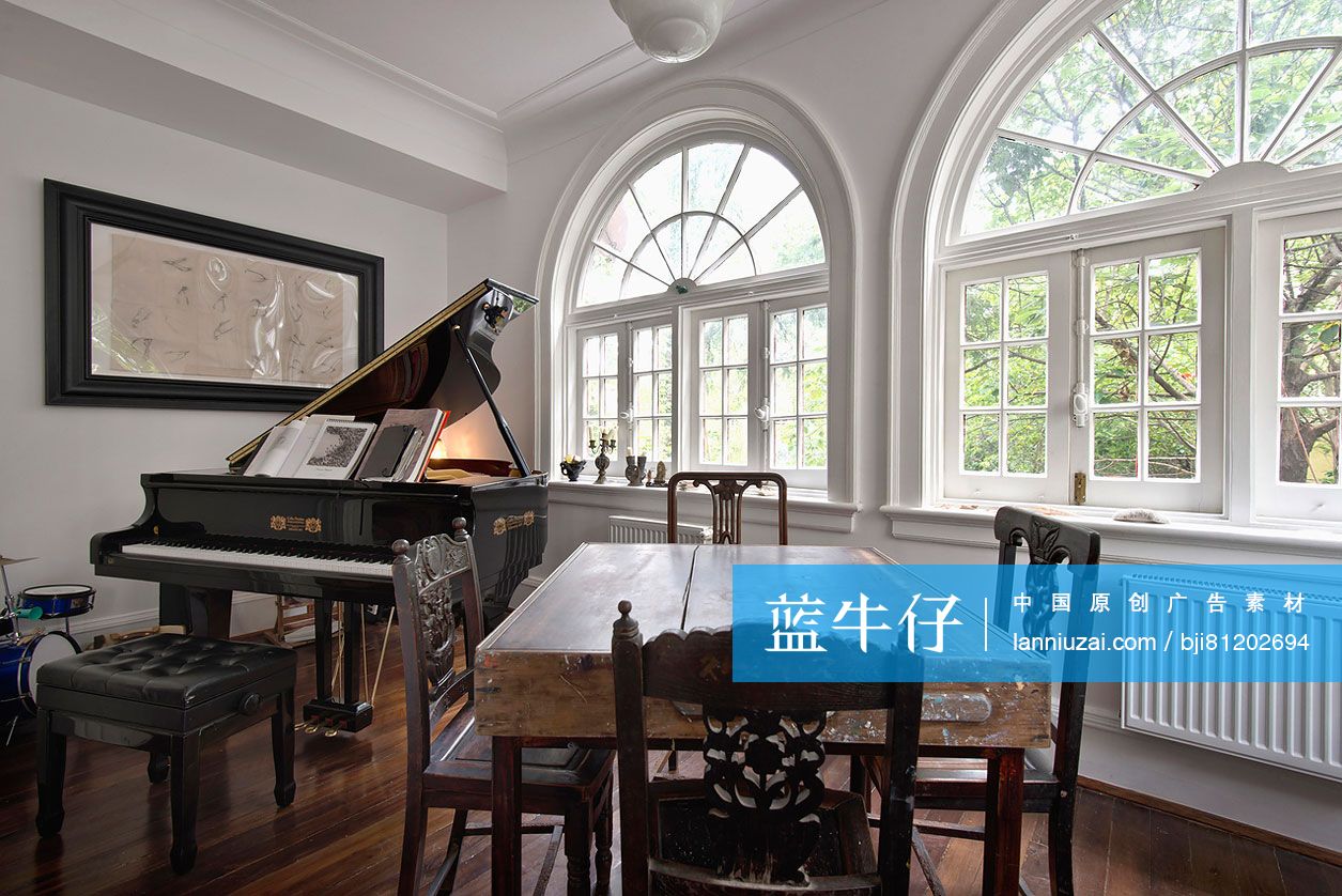 Chairs around wooden table with piano by arched French windows