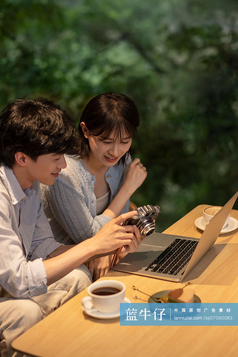 年轻情侣在咖啡馆查看相机上的照片