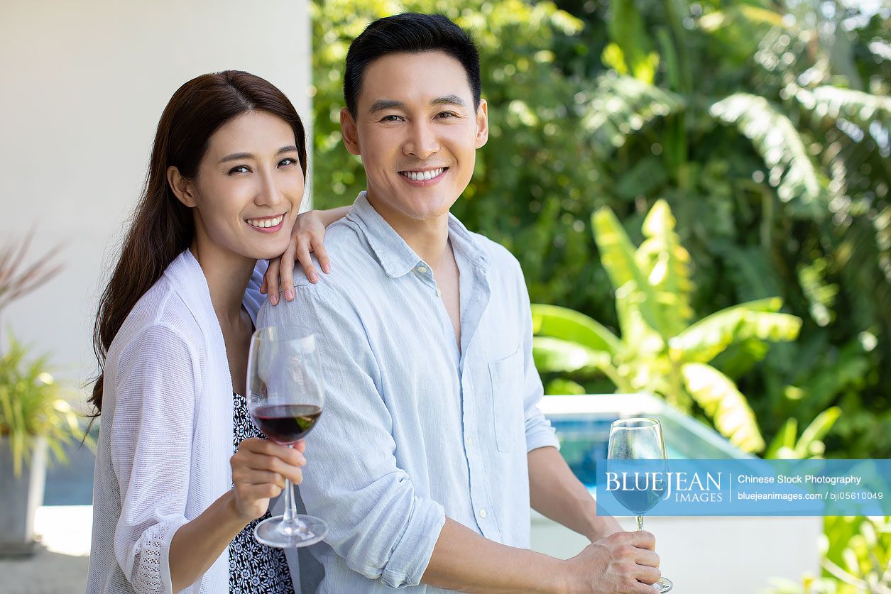 Happy young Chinese couple drinking wine on balcony
