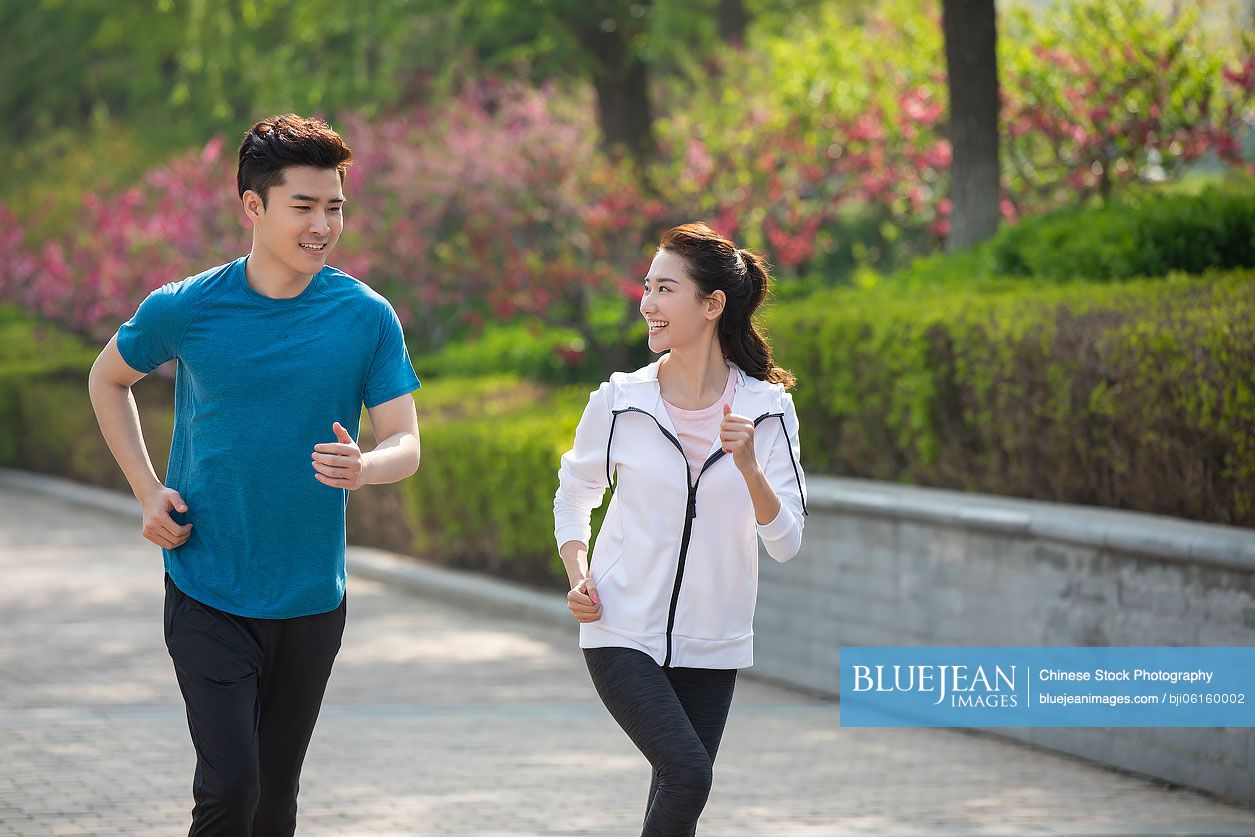 Happy young Chinese couple running in park