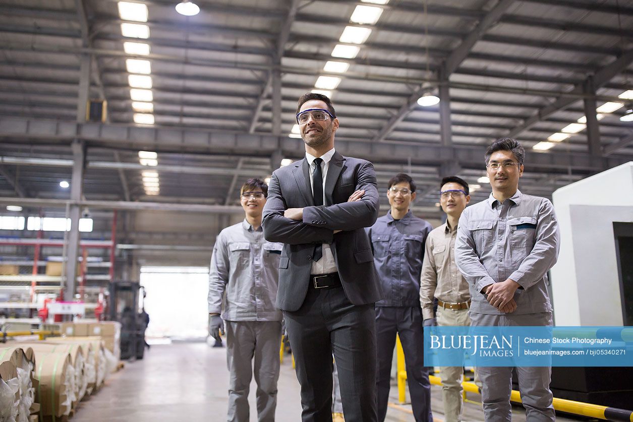 Confident businessman and engineering team in the factory