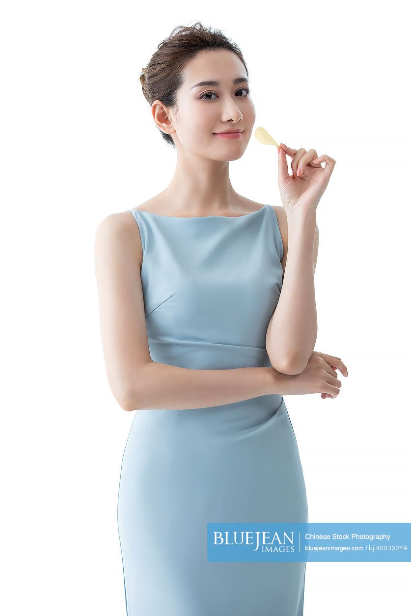 Beautiful young Chinese woman eating potato chip