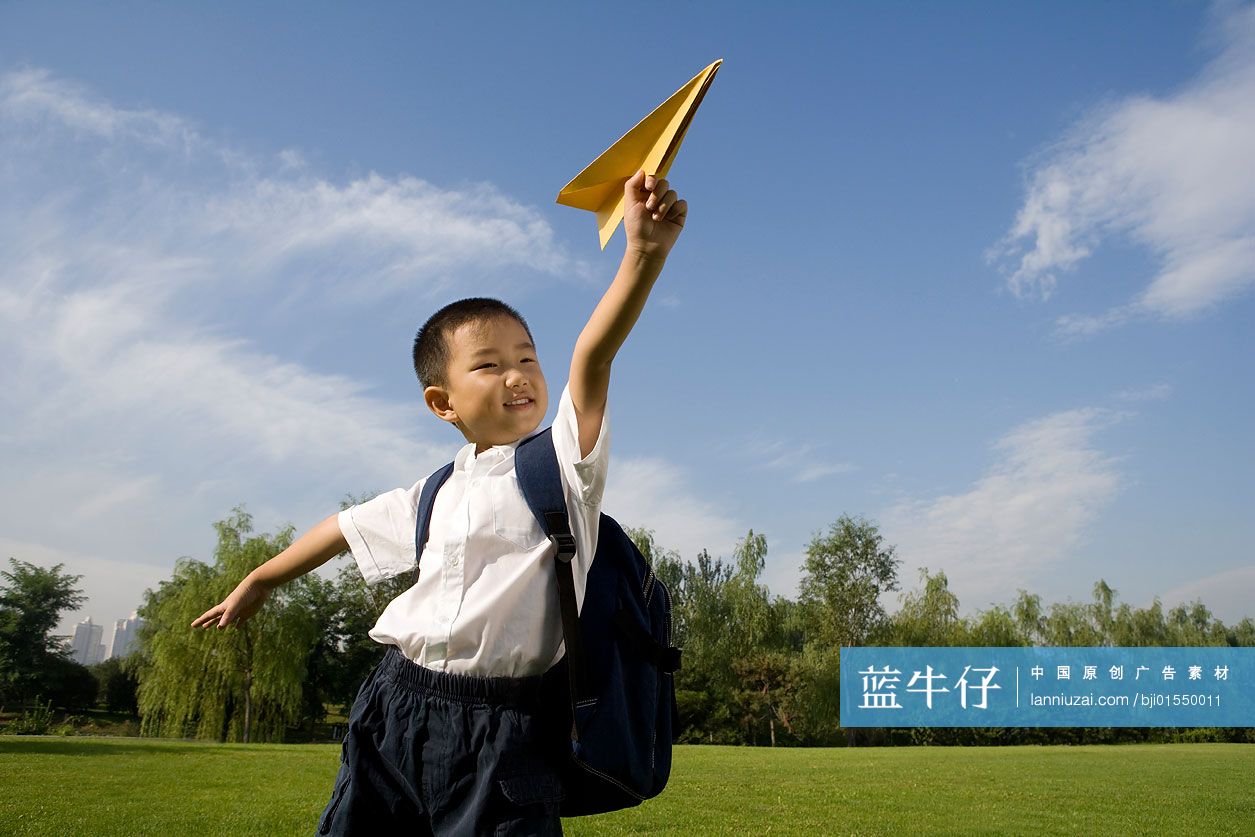 在草地上玩纸飞机的小男孩