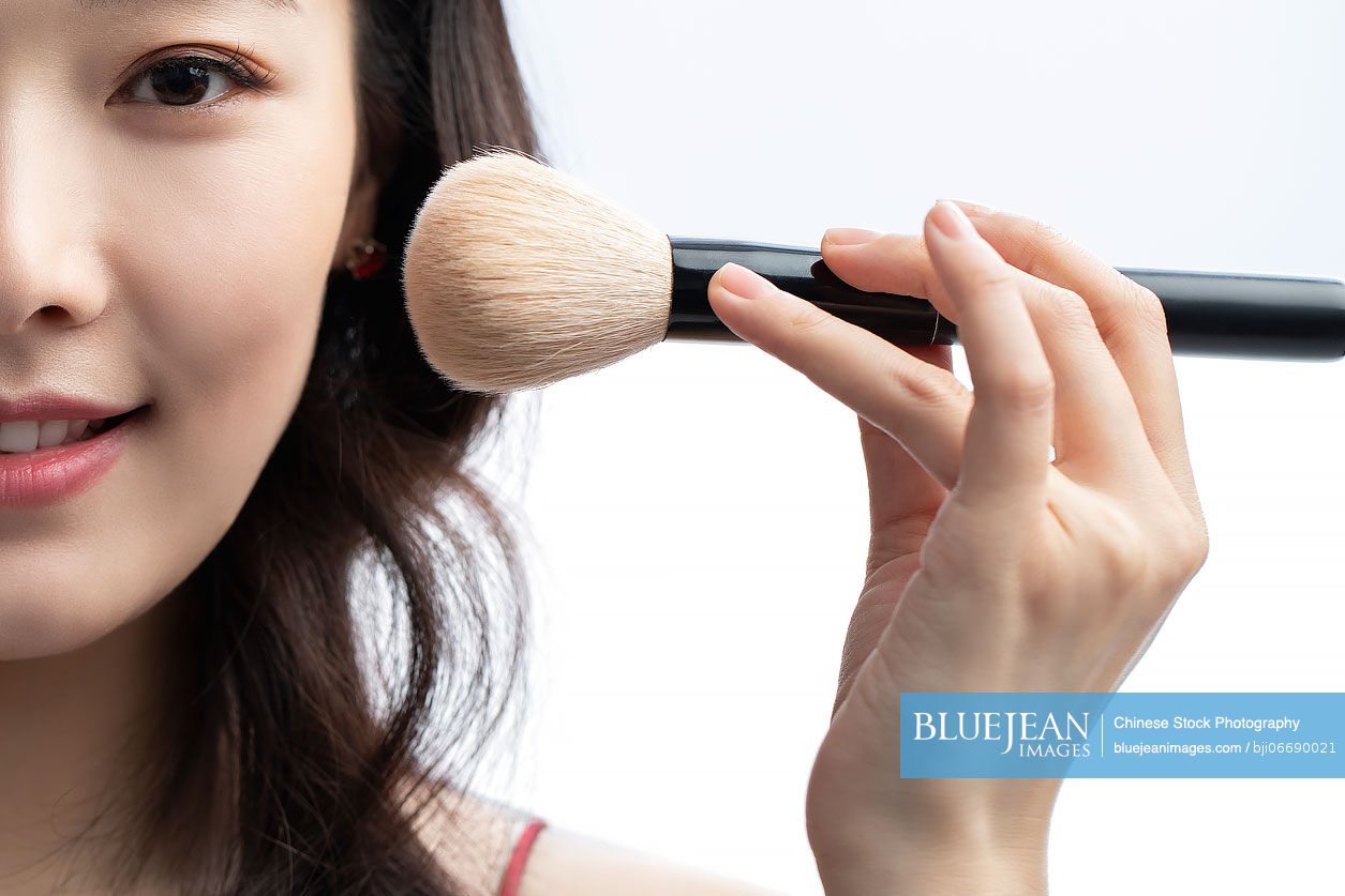 Young beautiful Chinese woman putting on make up