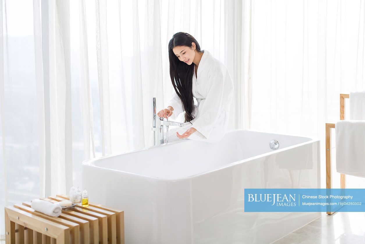 Young Chinese woman filling bathtub