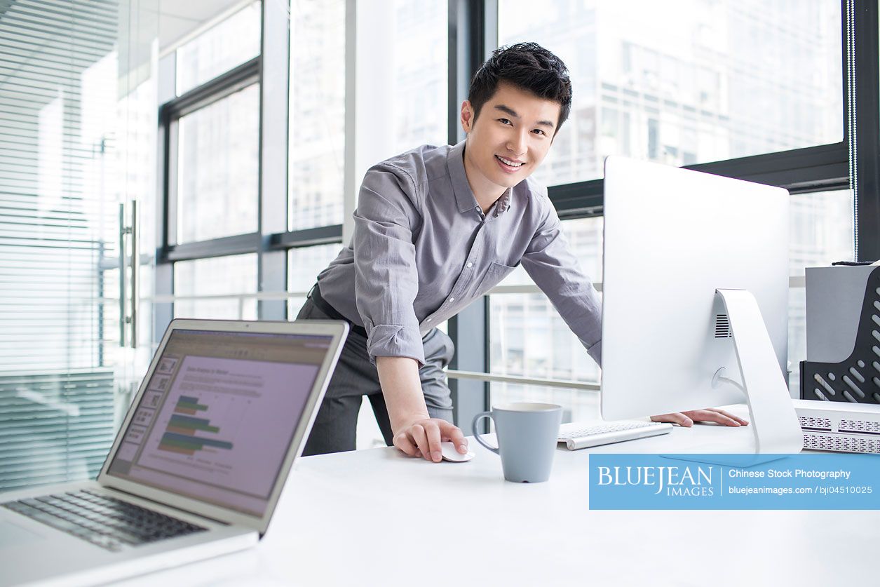 Young Chinese businessman using computer in office