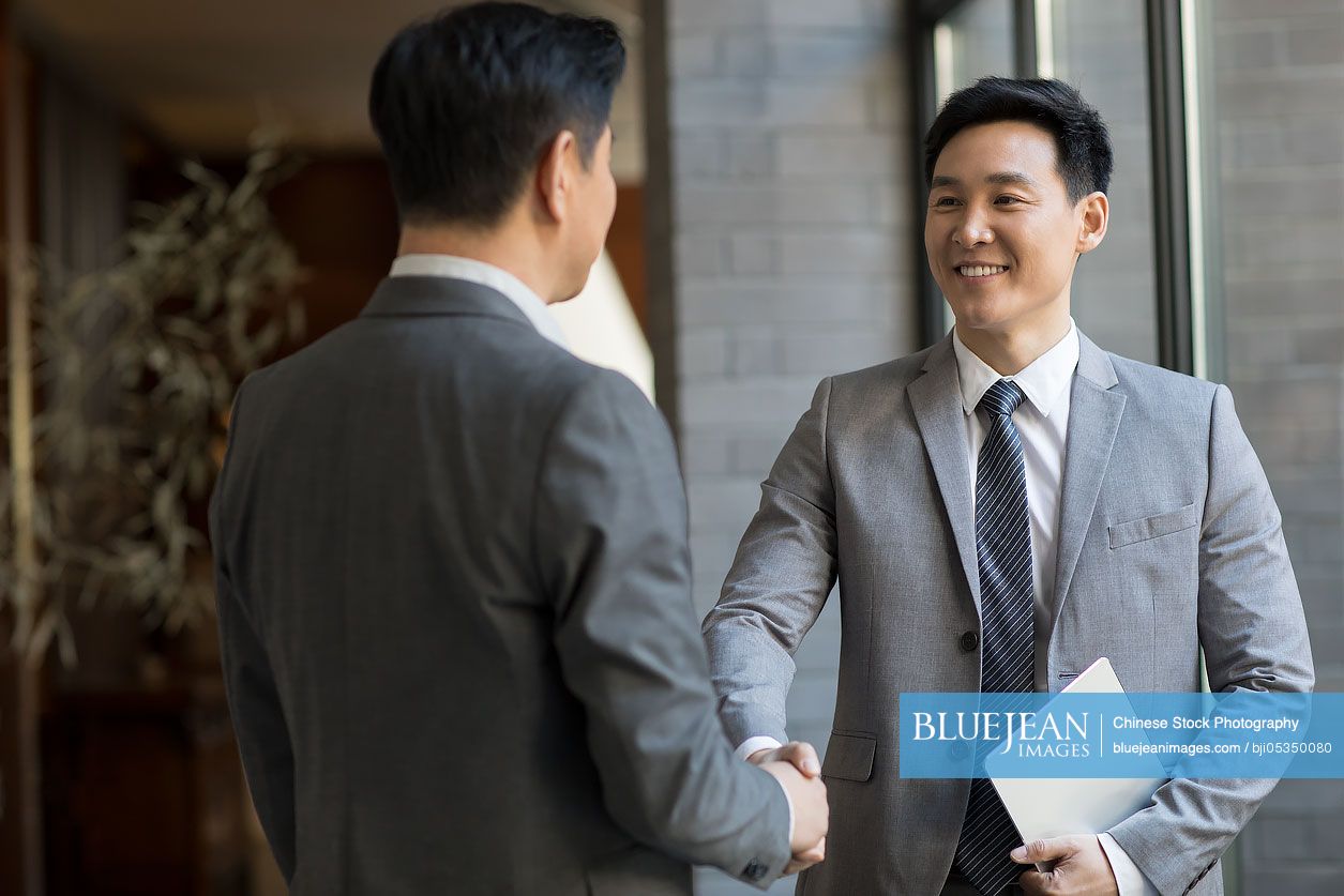 Cheerful Chinese businessmen shaking hands