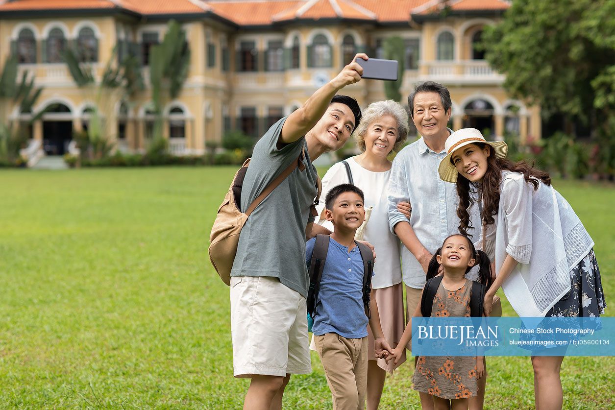 Happy Chinese family taking selfie on meadow