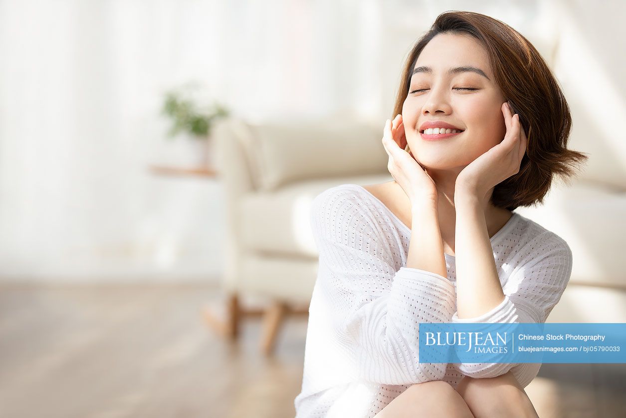 Happy young Chinese woman relaxing at home
