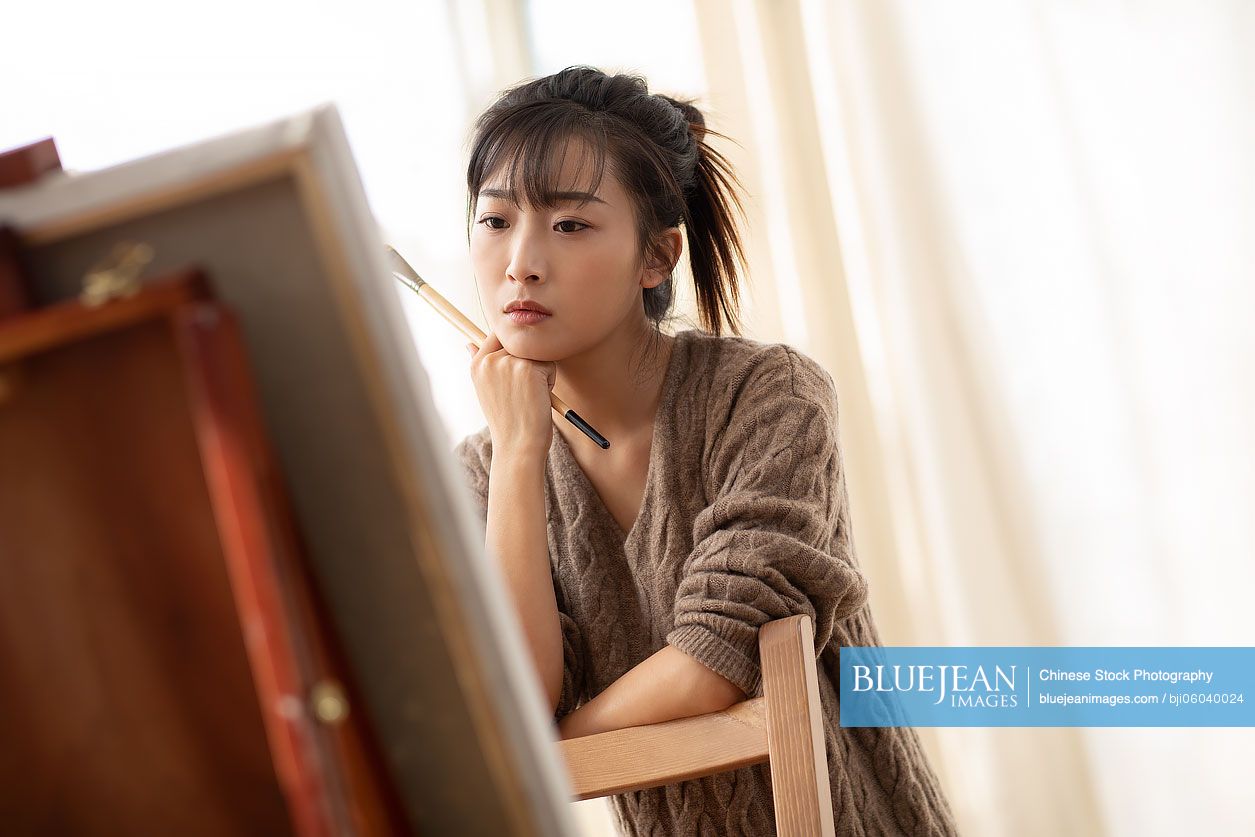 Young Chinese woman painting at home