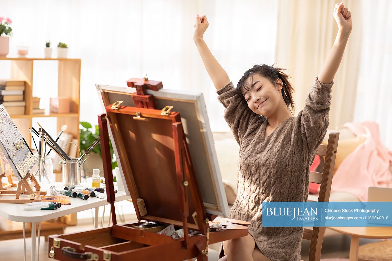 Young Chinese woman painting at home