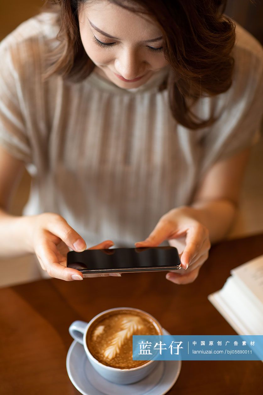 优雅女士在咖啡店使用手机拍照