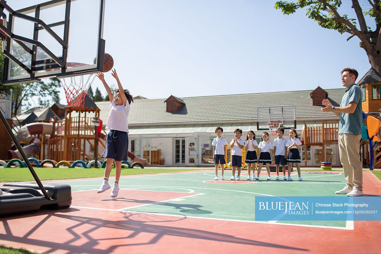 Foreign teacher and children playing basketball in playground