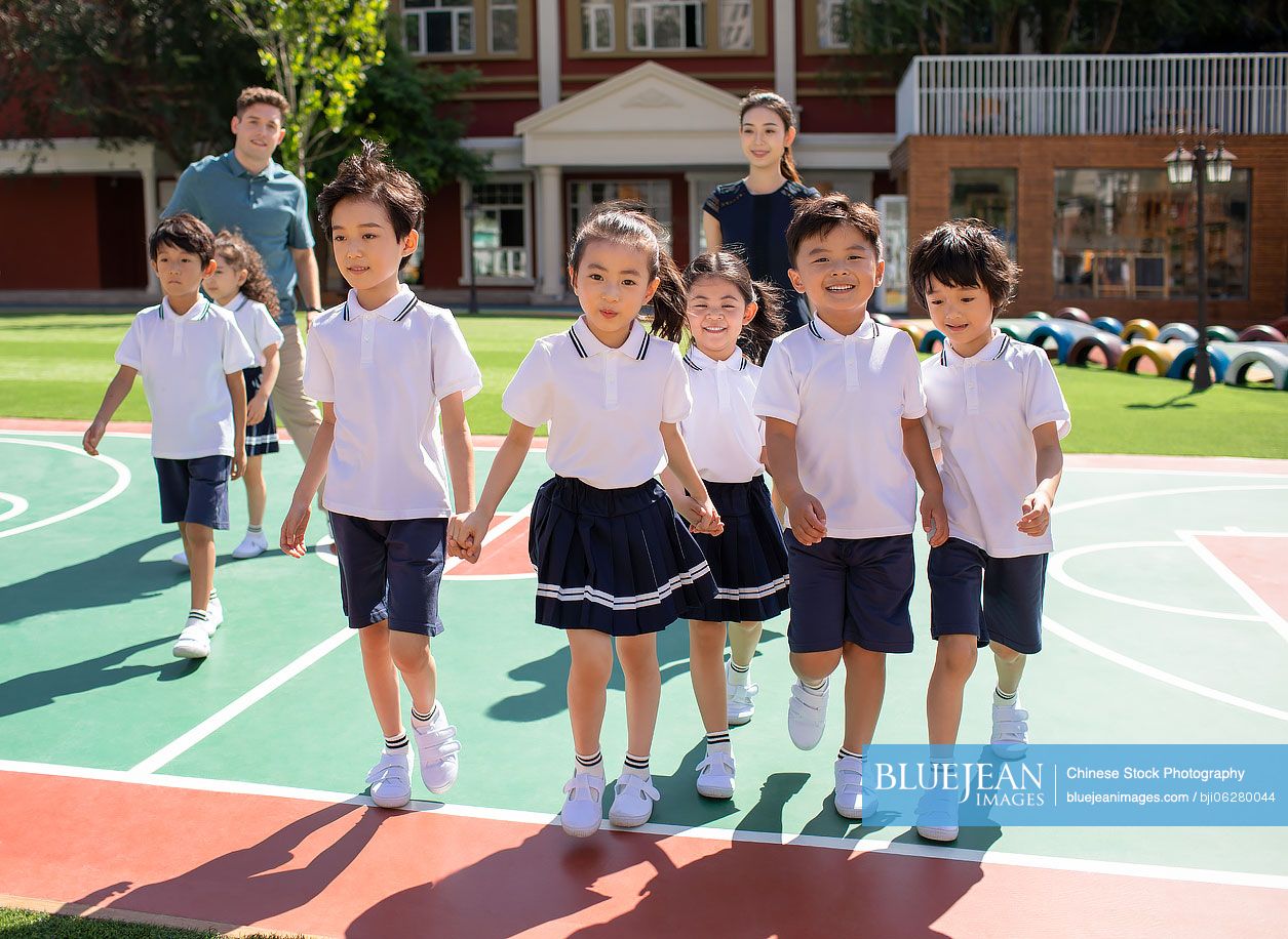 Teachers and children playing in kindergarten playground