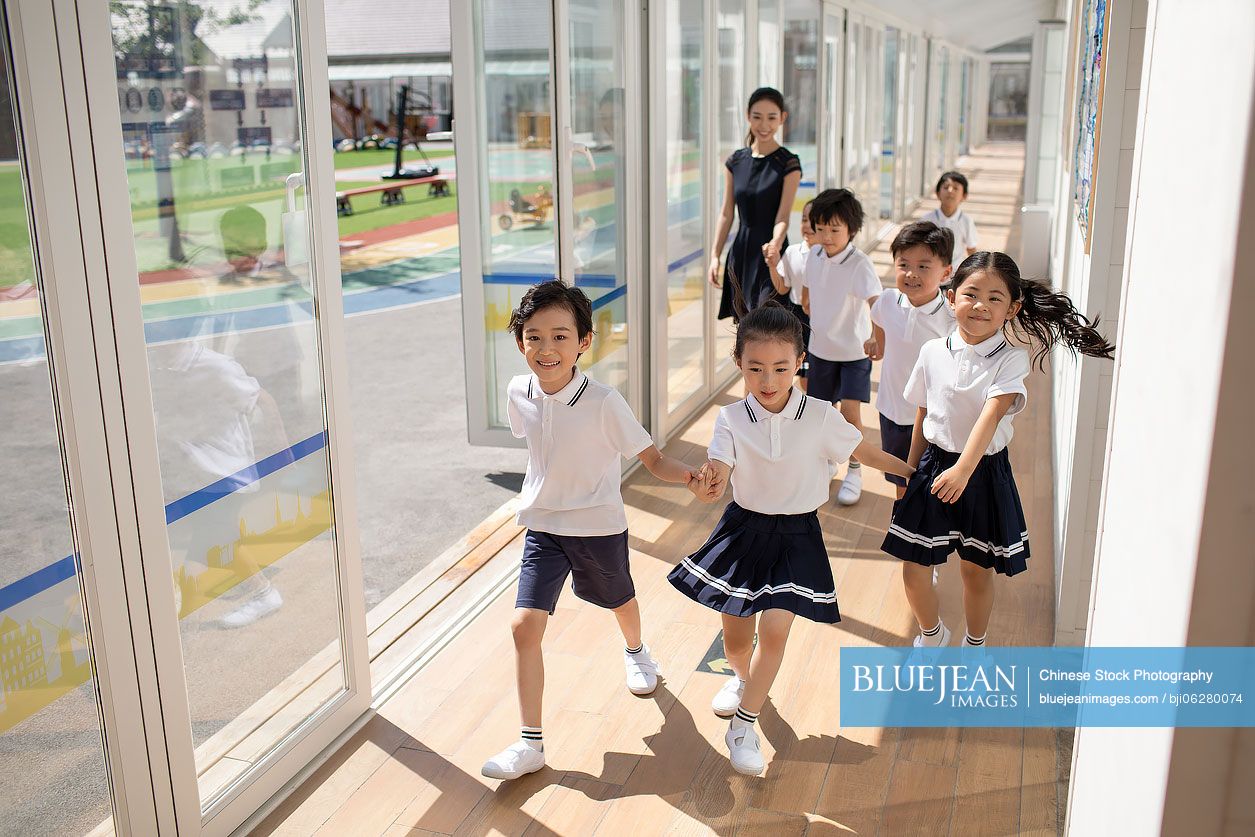 Chinese teacher and children in school hallway