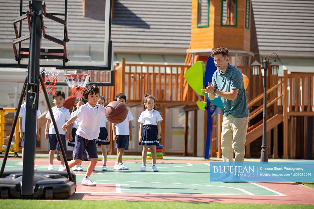 Foreign teacher and children playing basketball in playground